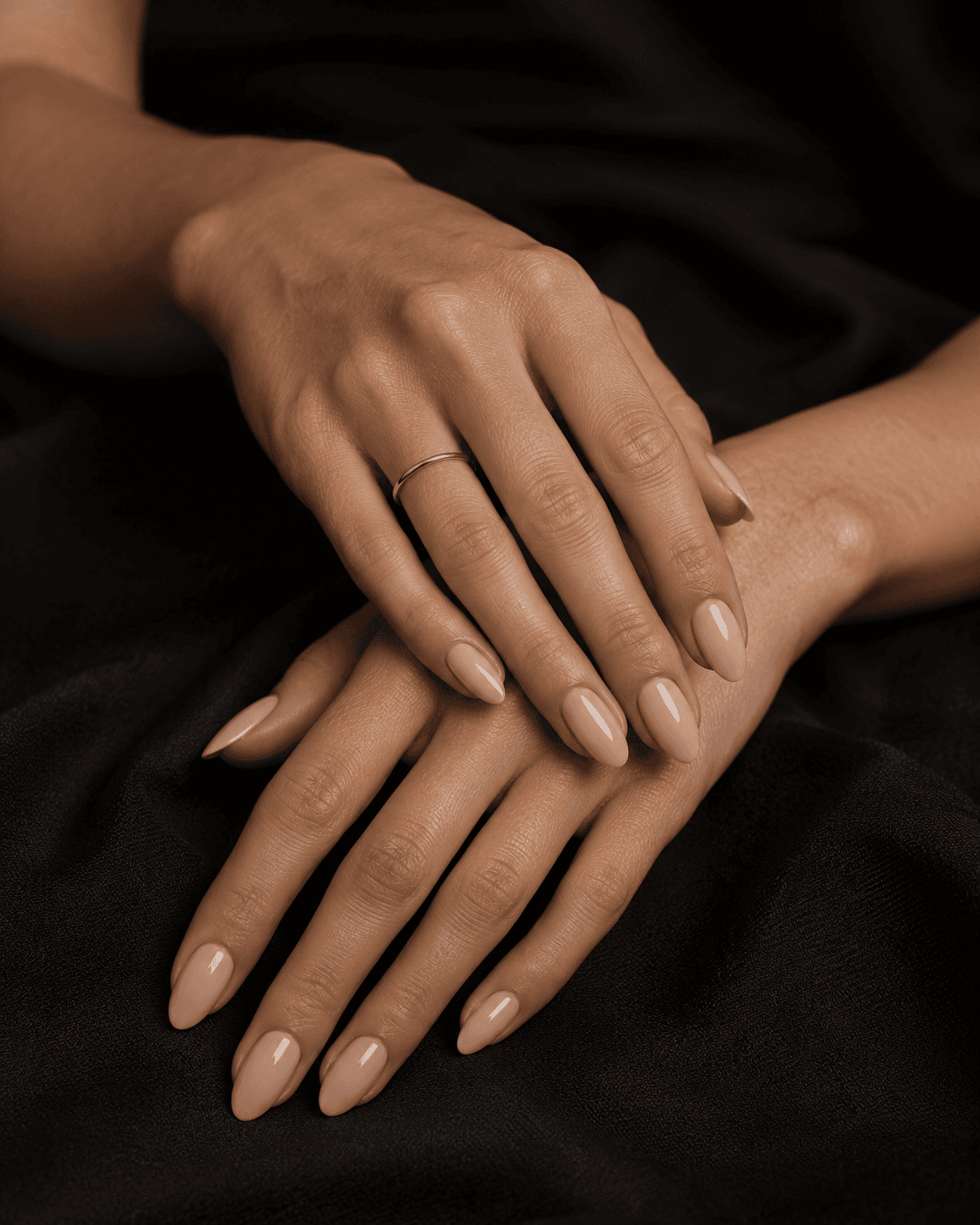 Manos con uñas almendradas y manicura nude.